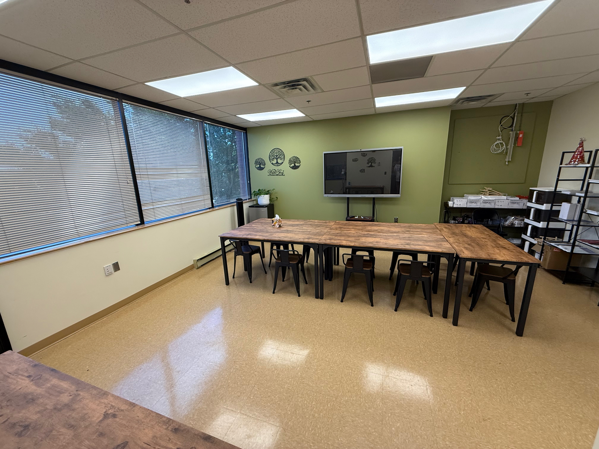 Meeting Room 1 at The Self Care Sanctuary Suites with a long wood table, seating, smart display and windows